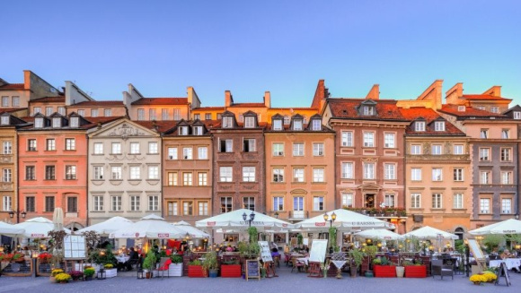 Outdoor market in Warsaw, Poland in front of tall Victorian buildings under a blue sky.