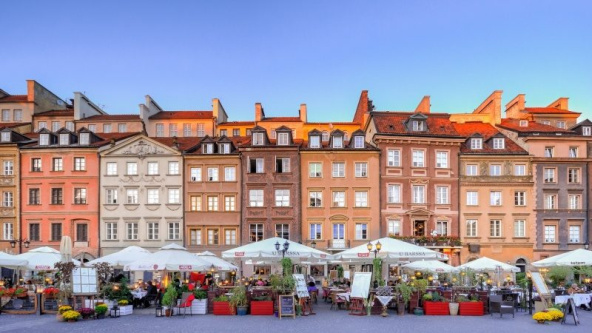 Outdoor market in Warsaw, Poland in front of tall Victorian buildings under a blue sky.