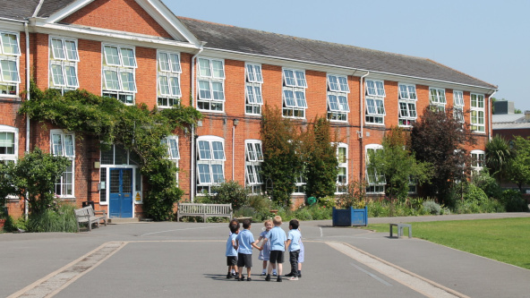 Pupils hold hands in a circle in the playground of Wimbledon Chase Primary
