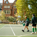 Two pupils play with a basketball on a tennis court at Wychwood School