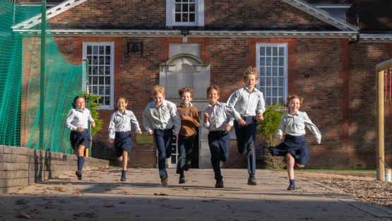 A group of smiling Amesbury pupils running down a pathway towards the photographer