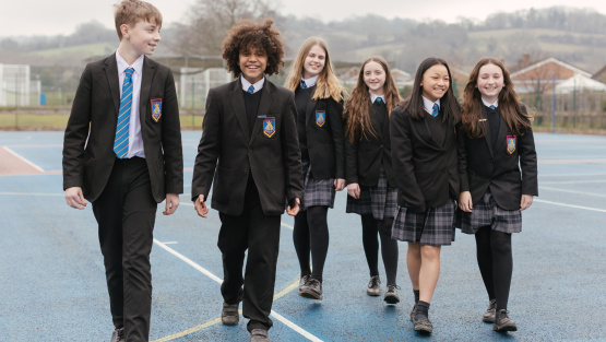 Pupils in uniform walking across netball court at Balcarras School, Cheltenham