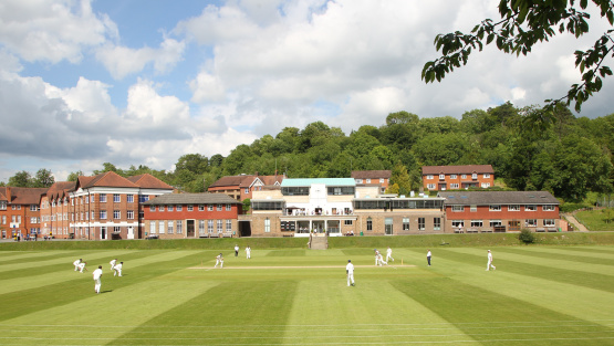 The view of Caterham School's main buildings with a cricket pitch in the foreground