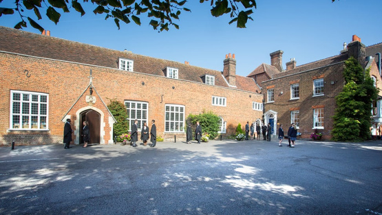 Pupils in gowns and school uniform outside the Old School and Swallow Library at Chigwell School
