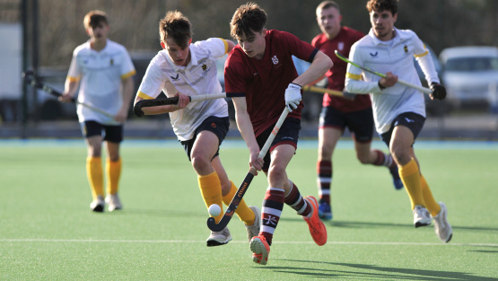 Dean Close hockey player dribbles with ball in match against Repton School