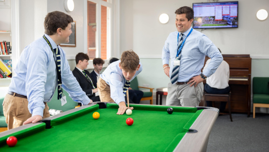 Eastbourne College pupils and a teacher playing pool in a boarding house