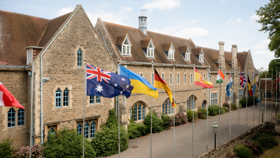 The exterior of the Europa School UK with a row of national flags flying from flagpoles in the foreground