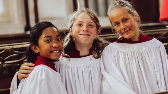 Three girl choristers in cassocks and surpliced from Exeter Cathedral School, Devon
