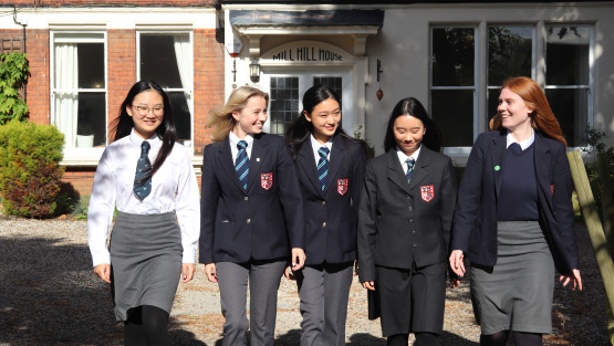 Female boarding pupils in uniform outside Mill Hill House at Brentwood School