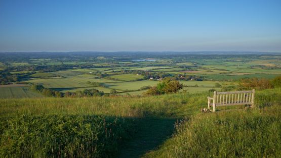 A single empty bench on South Downs National Park overlooking arlington reservoir and the East Sussex Weald