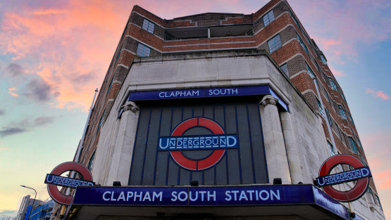 The frontage of Clapham South underground station. With a pinkish sunrise sky in the background.