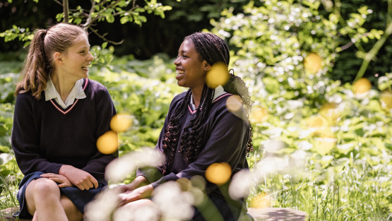 Two girls in uniform sit in the garden of James Allen Girls&rsquo; School