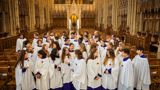 An image of Lancing College choir gathered together in the school chapel wearing cassocks and surplices