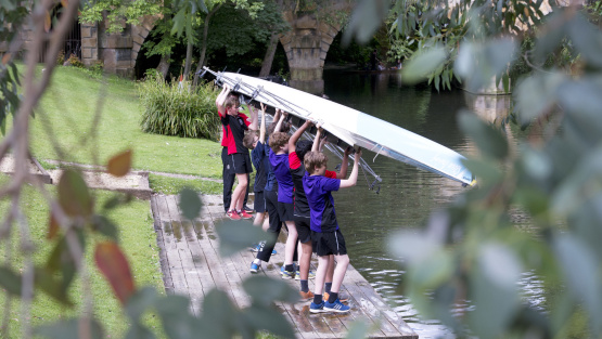 Magdalen College School rowers lowering a boat into the river