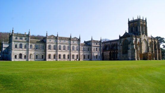 Exterior view of Milton Abbey surround by a large green lawn and blue skies.