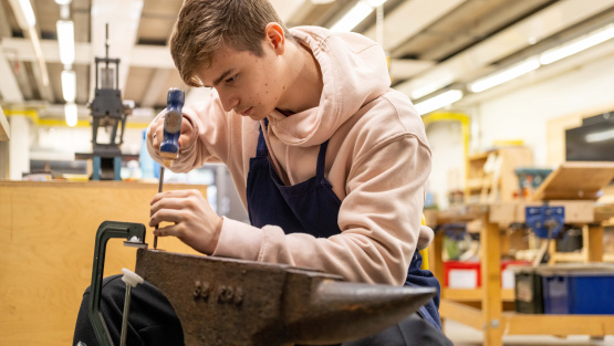 Male King Alfred pupil doing metal work on an anvil