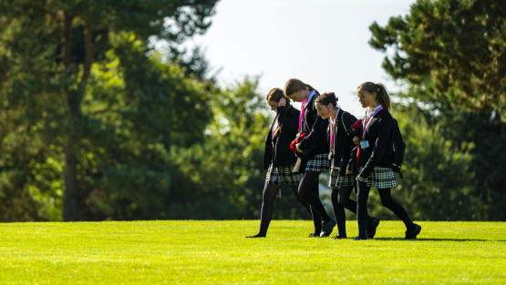 Four pupils in uniform walking across school lawns