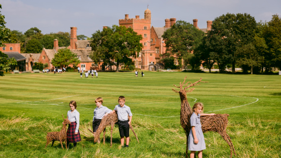 Exterior of Port Regis School grounds with young school children leaning on  a family of rattan dears