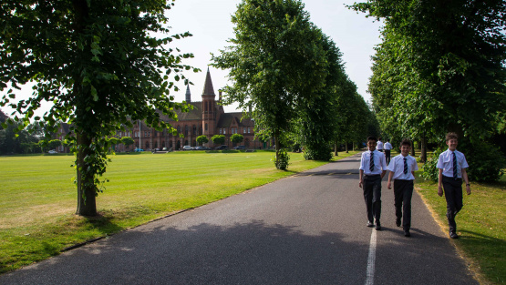 Pupils walking down the driveway of Reading School with the schools eye-catching readbrick neo-gothic architecture in the background