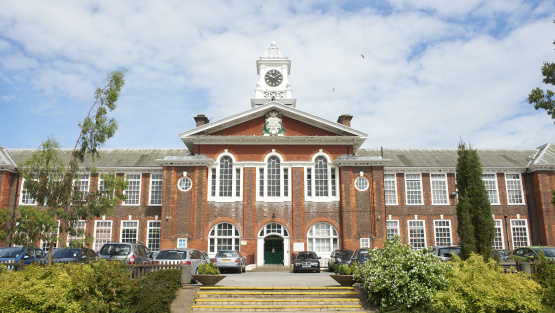 Exterior view of Royal Grammar School in Wycombe. The grounds include a car park at the entrance and shrubbery.