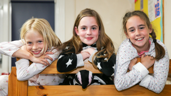 Girl boarders posing for a photo looking off the end of their dormitory bed