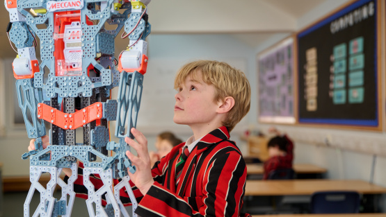 A male St Faith's pupil looks up at a Meccano robot.