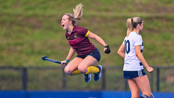 Female hockey player from Repton School jumps for joy while clutching her hockey stick